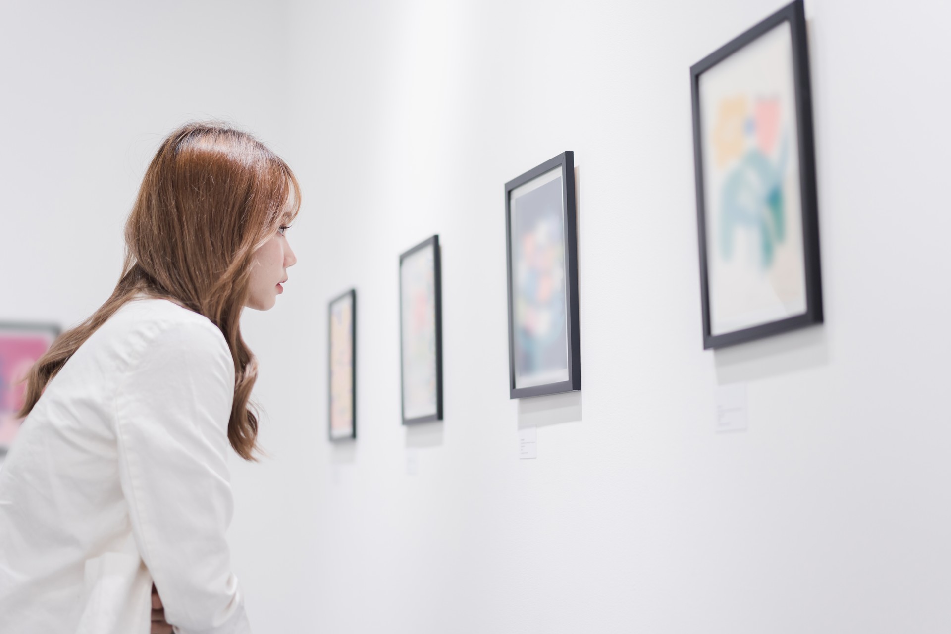 Woman visiting art gallery her looking pictures on wall watching photo frame painting at artwork museum people lifestyle concept.